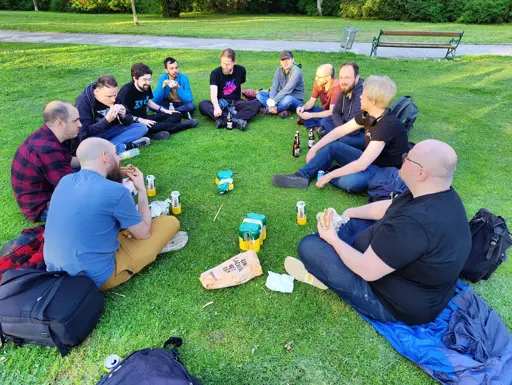 Group of KDE Plasma developers sitting in a circle on the grass in a park 