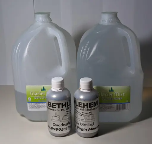 Two 200 mL bottles of mercury sit in front of two gallon jugs of water, one jug full and the other about a third full.