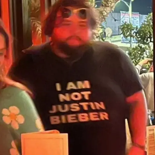 a guy wearing a shirt with "i am not Justin Bieber" written in all caps while standing in a line
